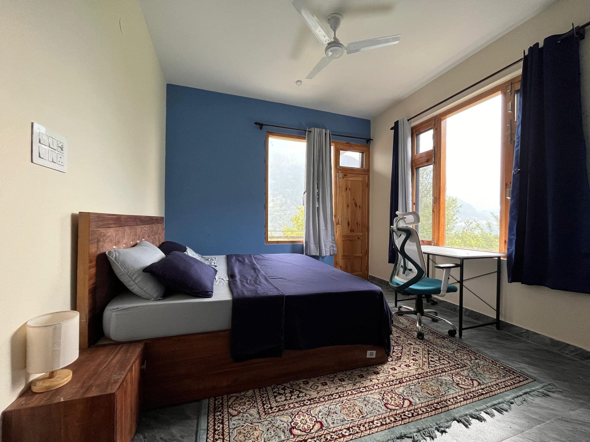 A bedroom at Mountain Child Home — wooden bed, blue accent wall, mountain view through the window